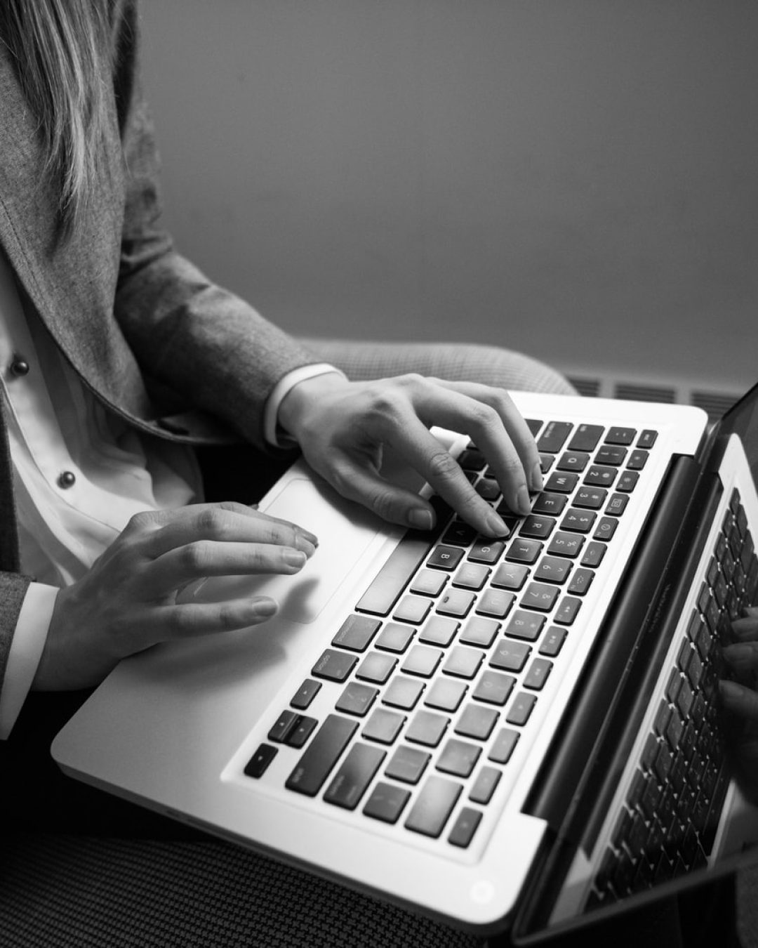 grayscale photography of woman typing on a laptop